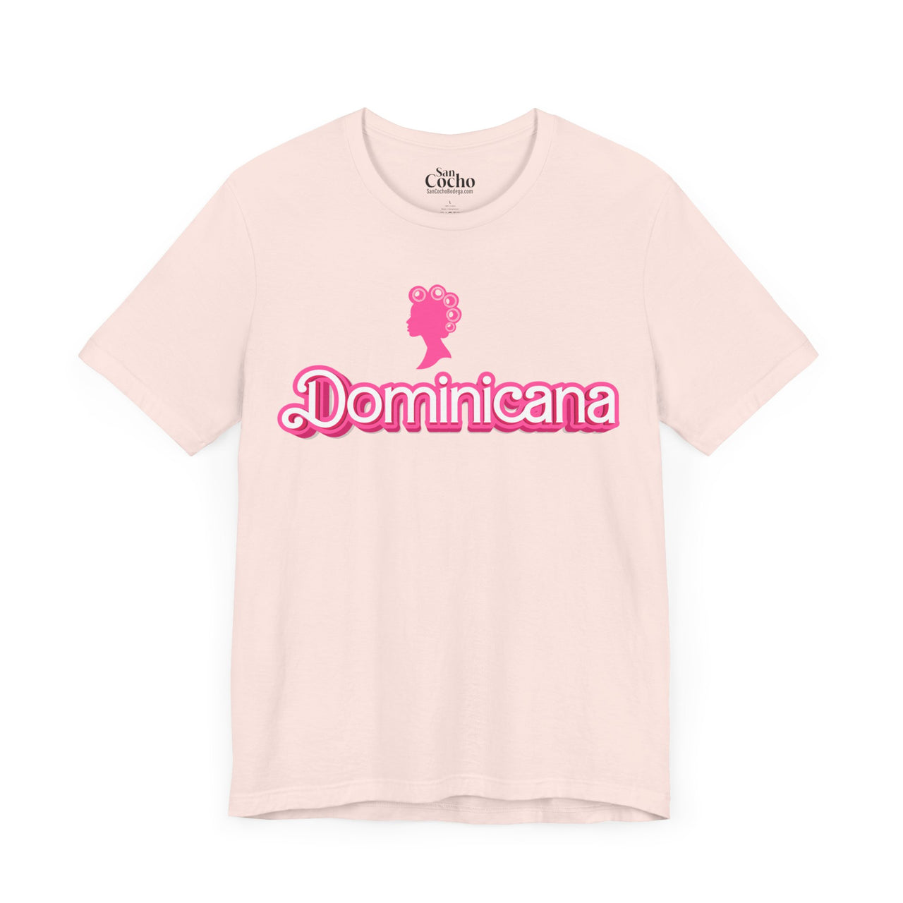 Light Pink Bella + Canvas 3001  t-shirt with a bold pink Barbie Style Font with the word 'Dominicana' text across the chest, featuring a Barbie style silhouette of a woman's head in hair curlers above the text, designed in a vibrant and playful style.