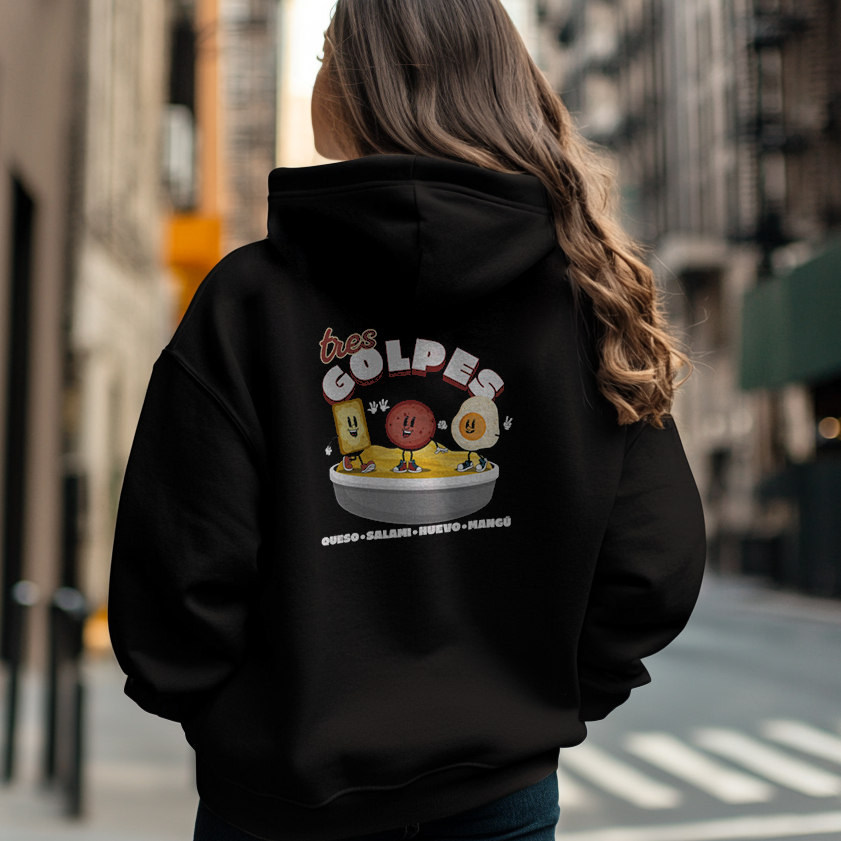 Back of a pretty Dominican woman wearing an oversized Gildan 18500 graphic hoodie with a vintage graphic of salami, juevos, and queso and the words "tres golpes" the famous Dominican breakfast on it