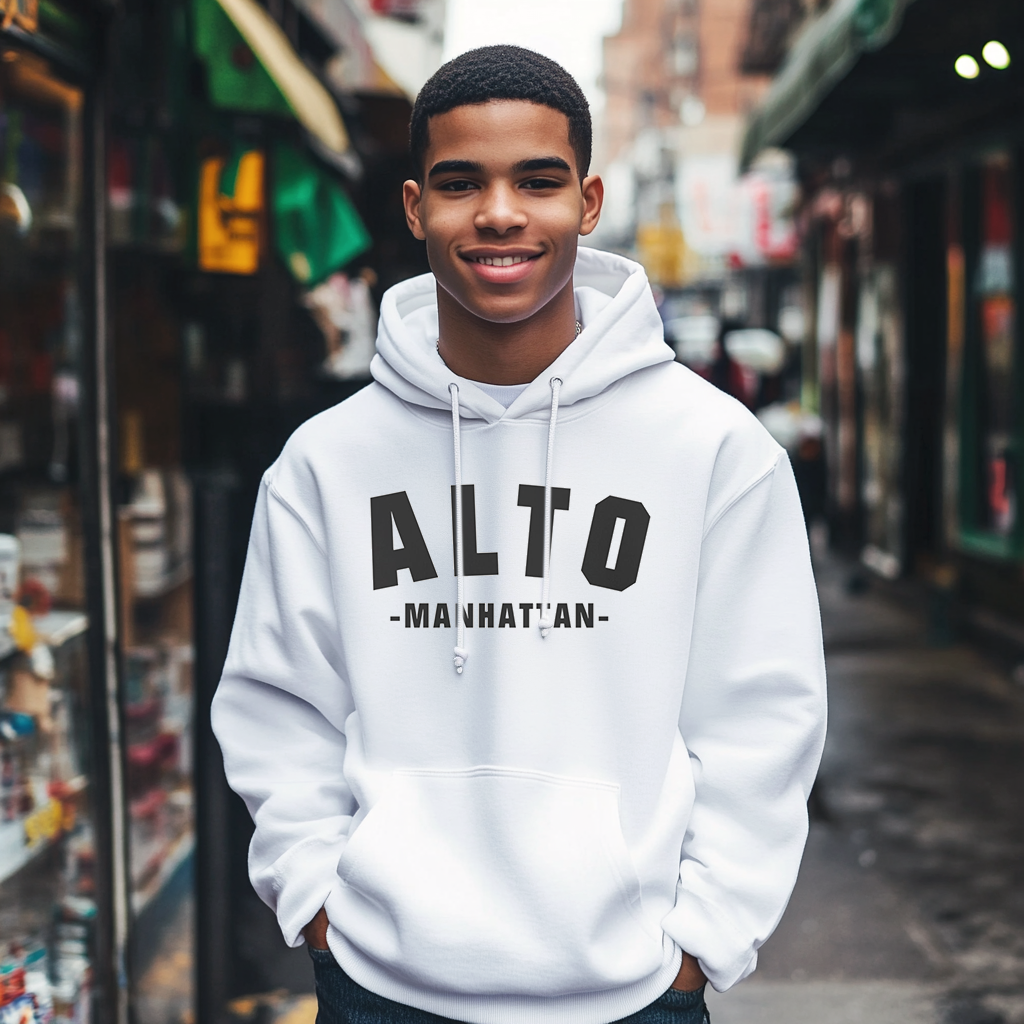 Good looking Dominican kid smiling wearing a Gildan 18500 graphic hoodie about Uptown  New York In a Vintage Collegiate font with the words "Alto Manhattan" on the front