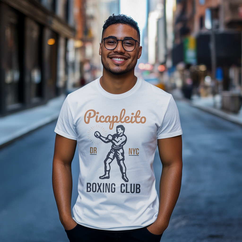 Handsome Dominican Papi wearing a Bella Canvas 3001 graphic tshirt with a vintage image of a guy in boxing gloves with the words "Picapleito DR NYC Boxing Club" on the front